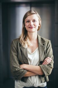 portrait-smiling-woman-with-arms-crossed-standing-against-wall