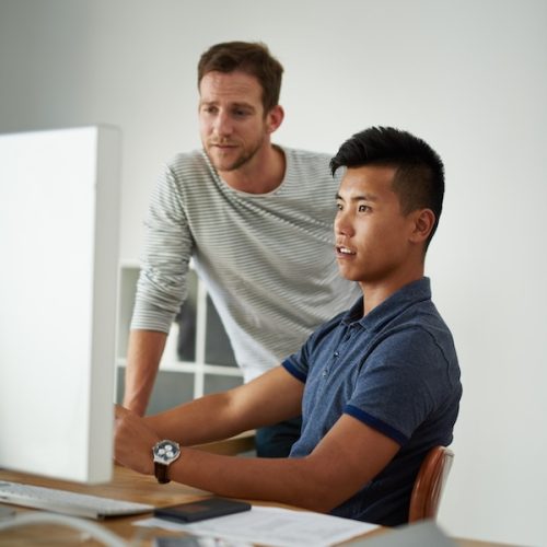 Team, business men and help on computer for training, creative or design on post production software. Tech, coaching or mentor teaching intern for video editing project, advice or feedback in startup.